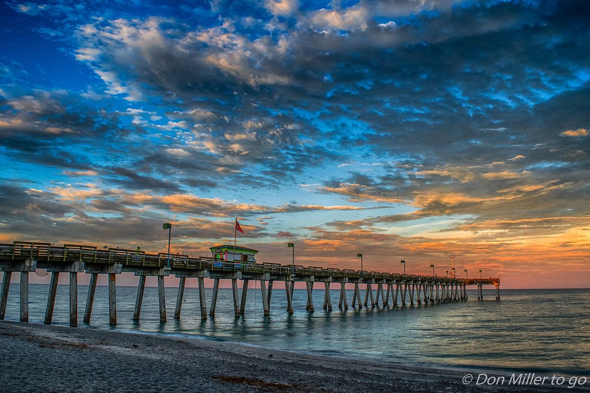 The Venice Fishing Pier stretching into the Gulf of Mexico under a colorful sunset sky
